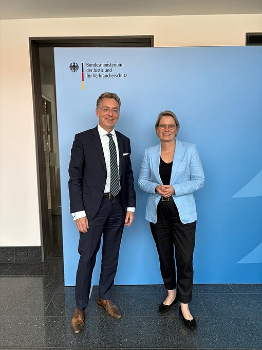 Christoph Safferling, Director of the Nuremberg Academy, stands next to Federal Minister of Justice and Consumer Protection Dr Stefanie Hubig in front of a roll-up banner featuring the Ministry.